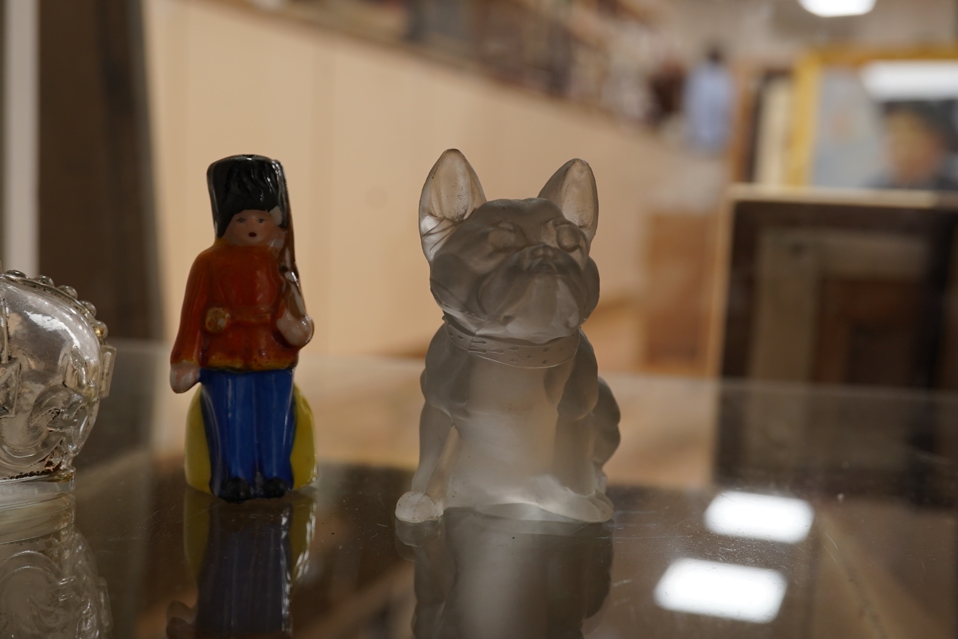 A collection of sundry items to include novelty glass bottles, devil pots and ceramic military caps